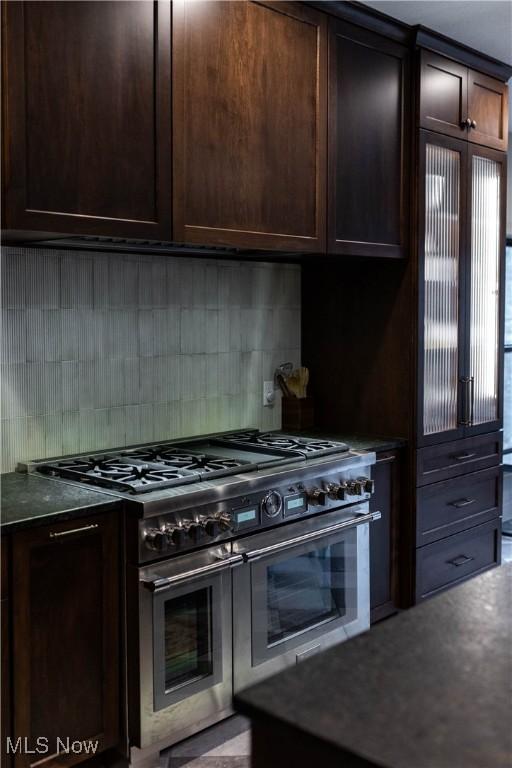 kitchen featuring dark brown cabinetry, double oven range, and backsplash