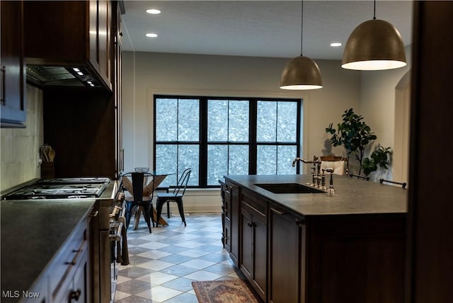 kitchen featuring dark brown cabinetry, sink, high end range, decorative light fixtures, and custom range hood