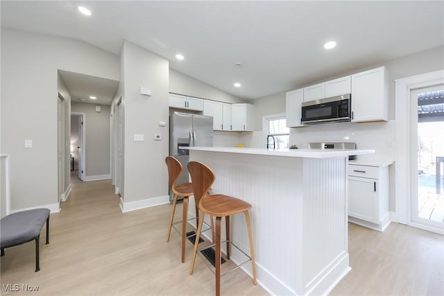 kitchen featuring white cabinets, stainless steel appliances, a kitchen island, and a wealth of natural light