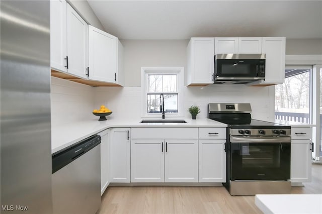 kitchen with white cabinetry, sink, light wood-type flooring, and appliances with stainless steel finishes