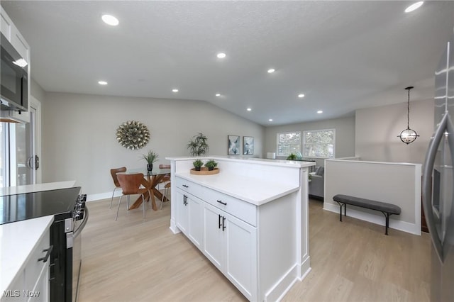 kitchen featuring stainless steel appliances, white cabinetry, pendant lighting, and light wood-type flooring