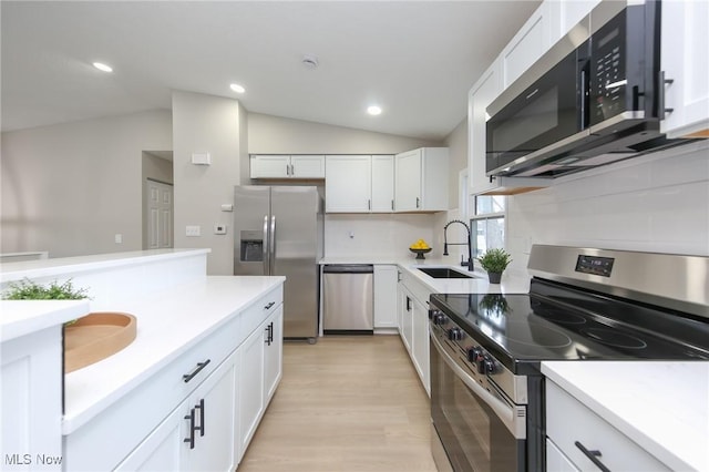 kitchen featuring sink, stainless steel appliances, vaulted ceiling, decorative backsplash, and white cabinets