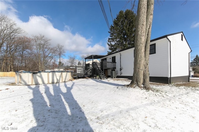 yard covered in snow with central AC unit and a deck