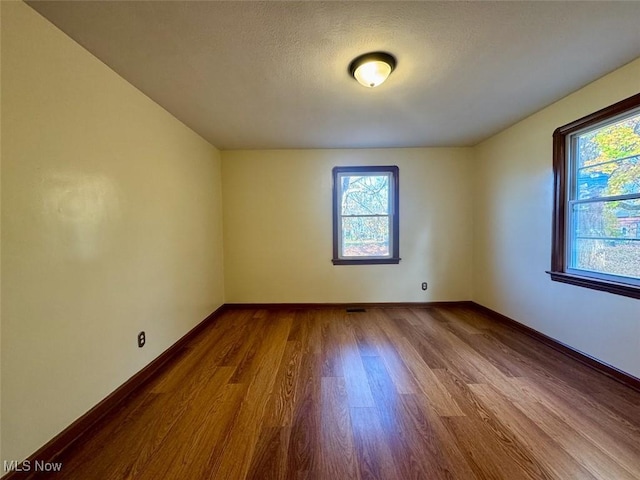 empty room with hardwood / wood-style flooring and a textured ceiling