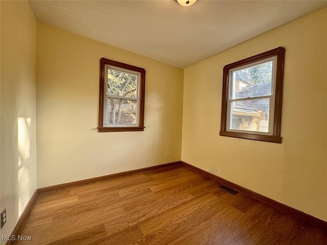 unfurnished room with a healthy amount of sunlight and light hardwood / wood-style floors