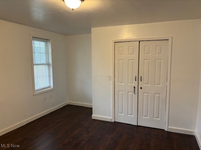 unfurnished bedroom featuring a closet and dark wood-type flooring