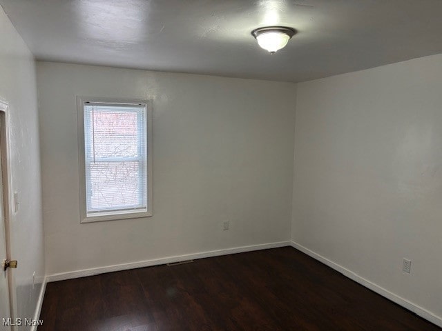 empty room with dark hardwood / wood-style flooring