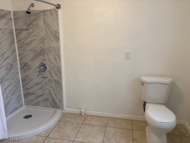 bathroom featuring tile patterned floors, toilet, and tiled shower