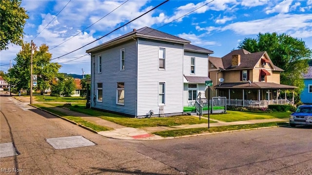 view of side of property with covered porch and a yard