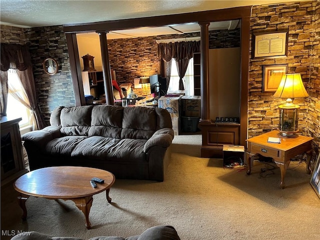 living room with carpet, a textured ceiling, and decorative columns