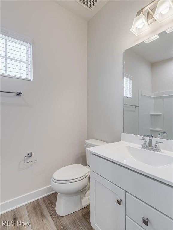 bathroom featuring a wealth of natural light, hardwood / wood-style flooring, toilet, and walk in shower