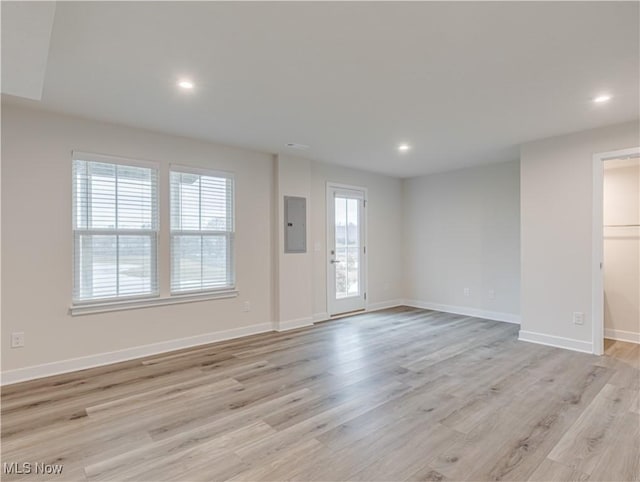 unfurnished room with a healthy amount of sunlight, light wood-type flooring, and electric panel