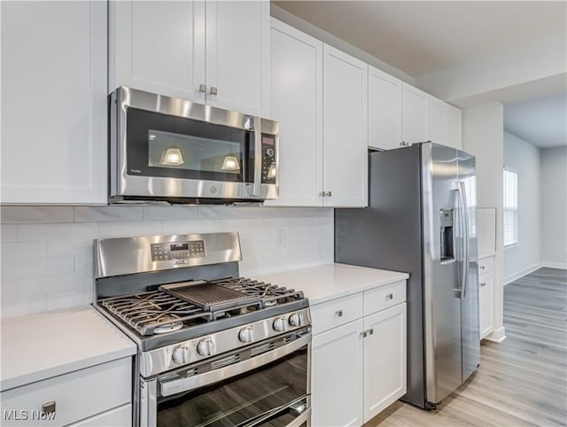 kitchen featuring decorative backsplash, white cabinetry, and appliances with stainless steel finishes