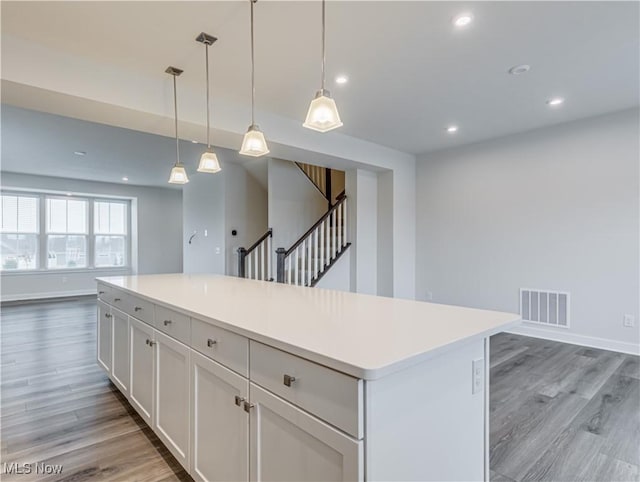 kitchen with pendant lighting, a center island, white cabinets, and light hardwood / wood-style flooring