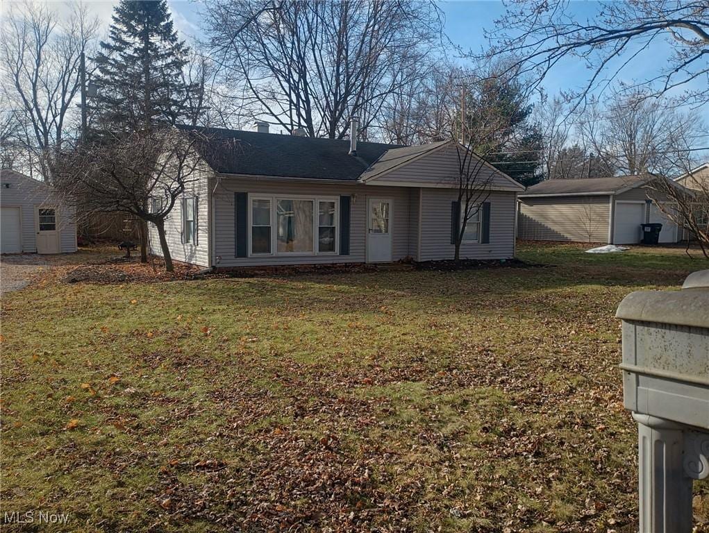 single story home with a garage, an outbuilding, and a front yard