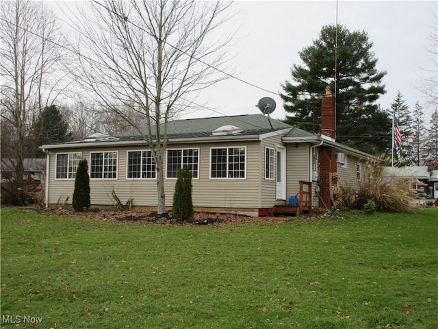 rear view of property featuring a lawn