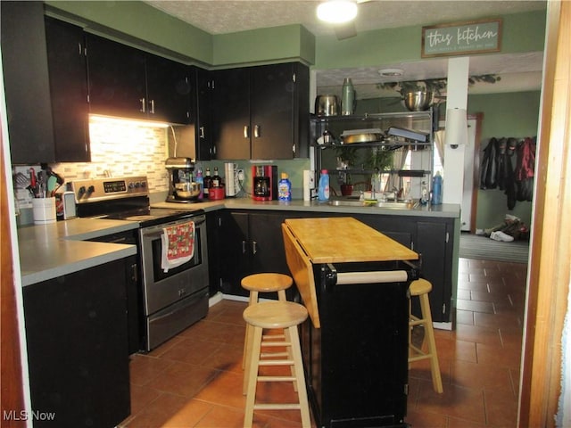 kitchen with a breakfast bar area, electric range, and tile patterned flooring