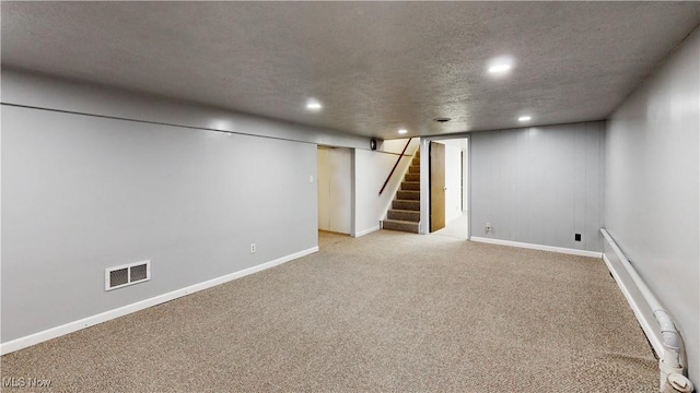 basement with a textured ceiling, light colored carpet, and a baseboard heating unit