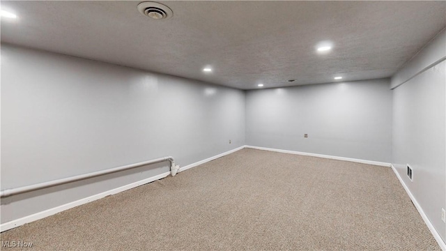 basement featuring carpet flooring, a textured ceiling, and a baseboard heating unit