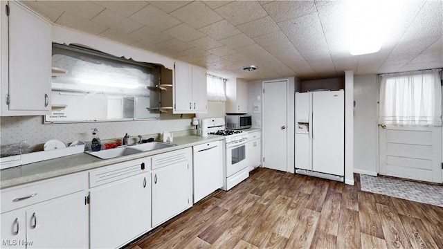 kitchen featuring sink, a healthy amount of sunlight, white appliances, white cabinets, and hardwood / wood-style flooring