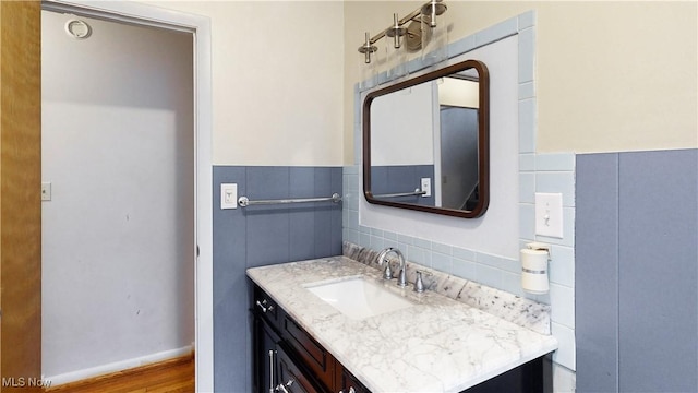 bathroom featuring vanity, wood-type flooring, and tile walls