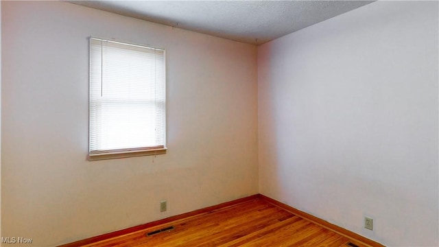 spare room with light wood-type flooring and a textured ceiling