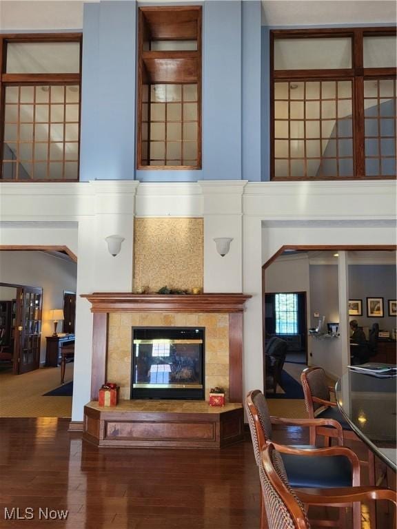 living room with a towering ceiling, a fireplace, and dark wood-type flooring