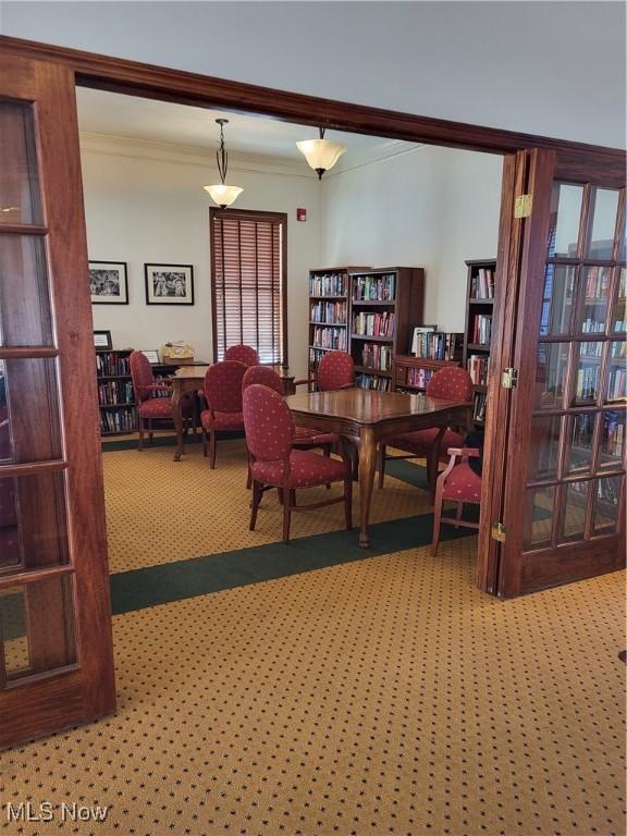 carpeted dining space with crown molding