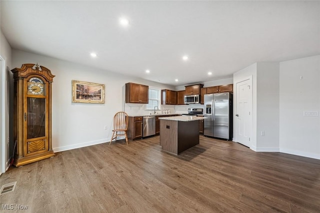 kitchen with sink, dark wood-type flooring, a kitchen breakfast bar, a kitchen island, and appliances with stainless steel finishes