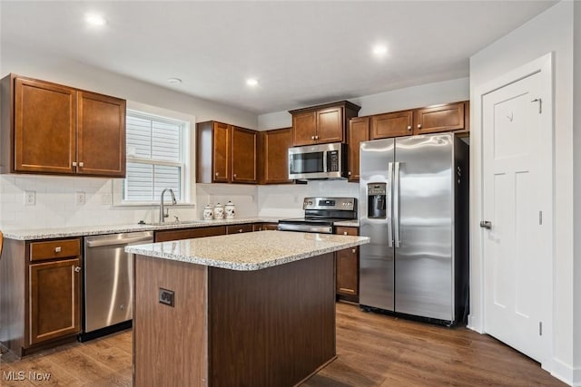 kitchen with a center island, sink, dark hardwood / wood-style floors, tasteful backsplash, and stainless steel appliances