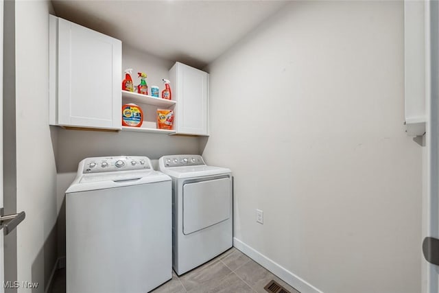 clothes washing area featuring cabinets, independent washer and dryer, and light tile patterned floors