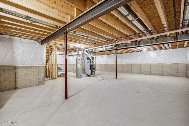 basement featuring electric water heater, heating unit, and brick wall