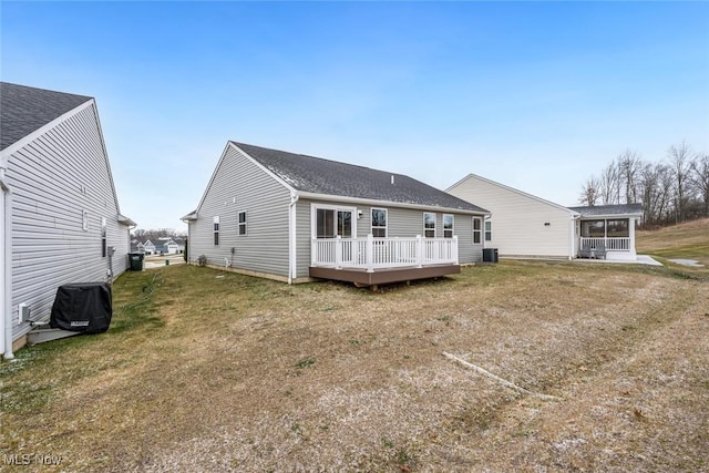 rear view of property with a sunroom, cooling unit, a deck, and a lawn