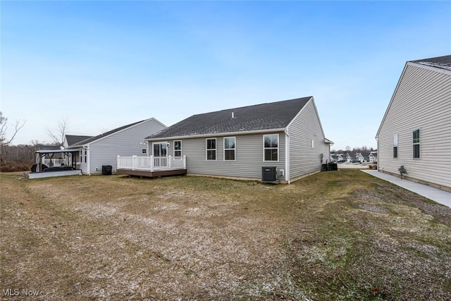 rear view of property featuring a lawn, central AC unit, and a deck