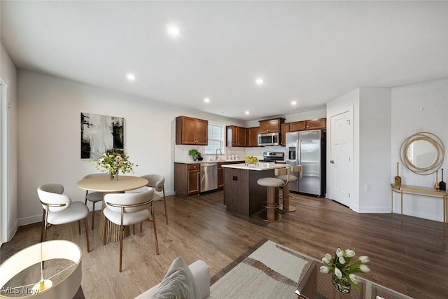 interior space featuring a center island, sink, dark wood-type flooring, stainless steel appliances, and a kitchen breakfast bar