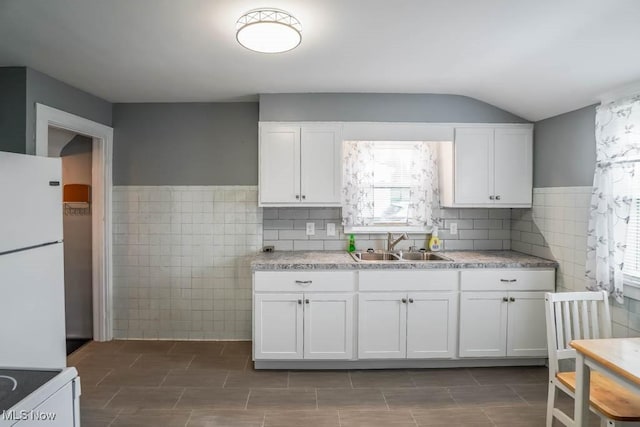 kitchen featuring white cabinetry, sink, tile walls, and white refrigerator