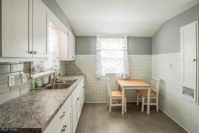 kitchen featuring white cabinetry, sink, and tile walls