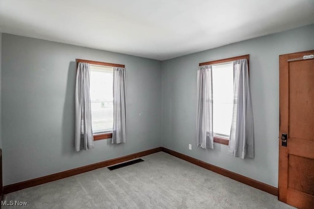 empty room featuring light colored carpet and a healthy amount of sunlight