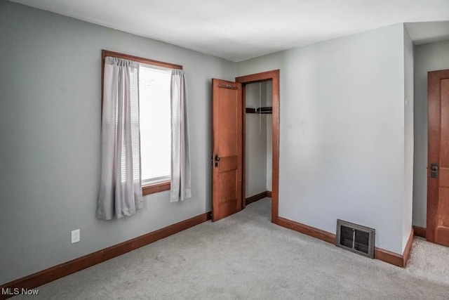 unfurnished bedroom with light carpet and a closet