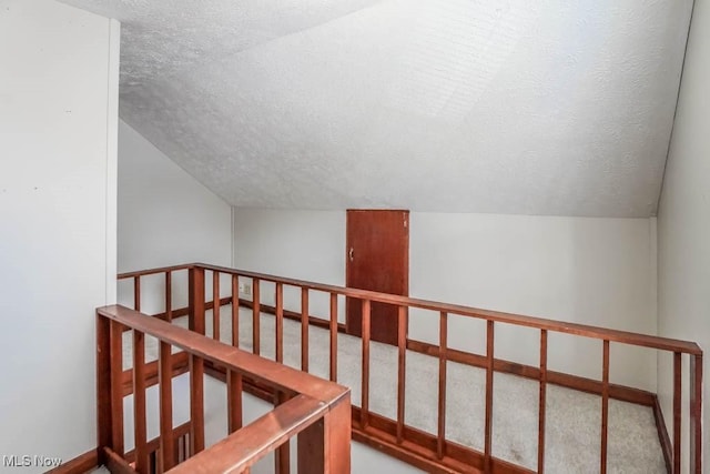 interior space with a textured ceiling and vaulted ceiling