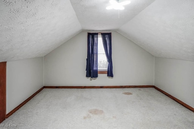 additional living space featuring carpet, a textured ceiling, and lofted ceiling