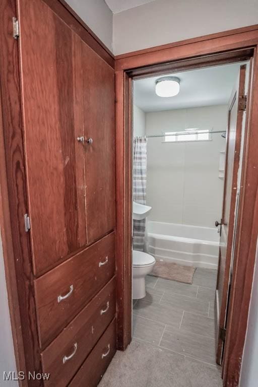 bathroom with shower / tub combo with curtain and toilet