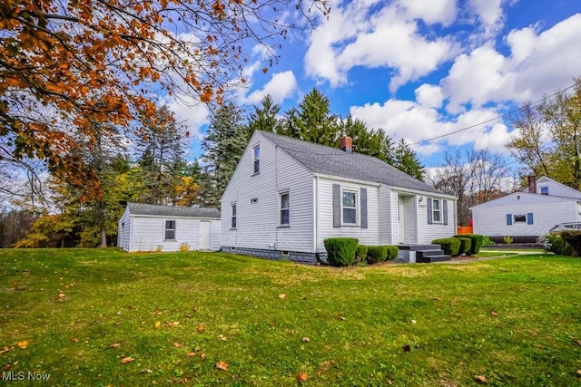 rear view of property with a lawn and an outbuilding