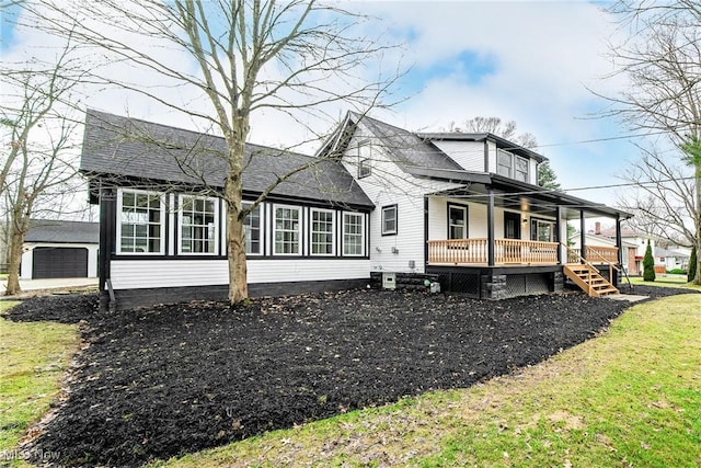 view of property exterior with a lawn, a garage, covered porch, and an outbuilding