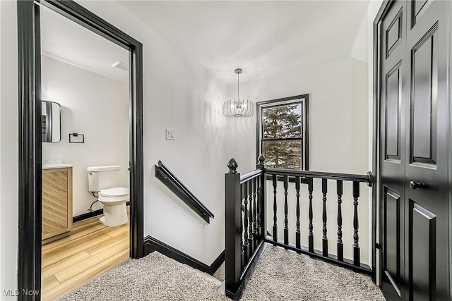 stairs featuring hardwood / wood-style flooring and an inviting chandelier