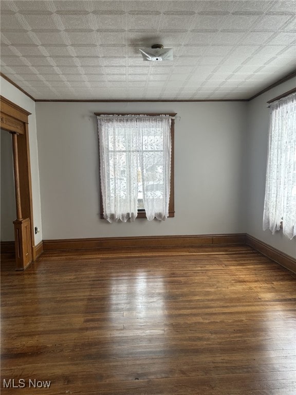 spare room featuring dark hardwood / wood-style flooring and crown molding