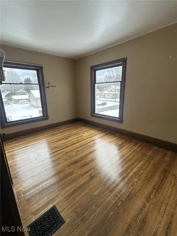 spare room featuring a healthy amount of sunlight and hardwood / wood-style flooring