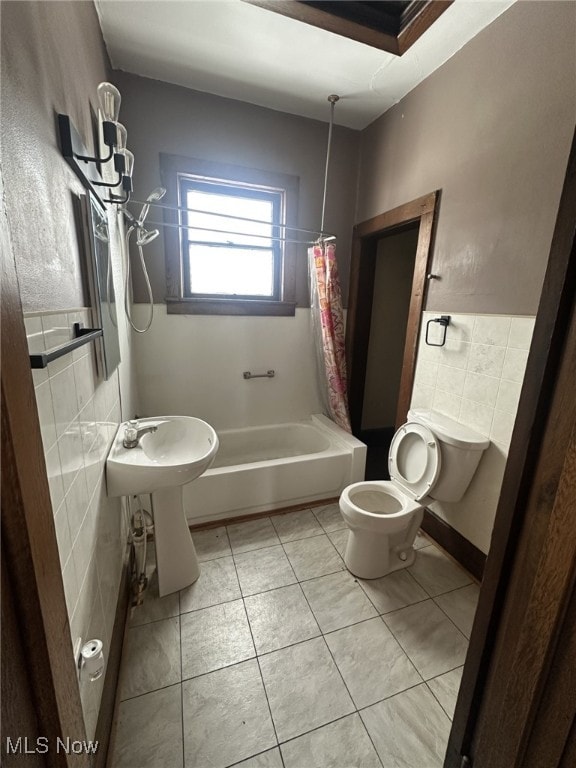 bathroom featuring tile patterned floors, shower / bath combo with shower curtain, tile walls, and toilet