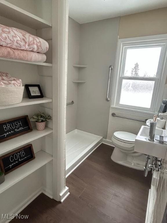 bathroom with hardwood / wood-style flooring, toilet, and walk in shower