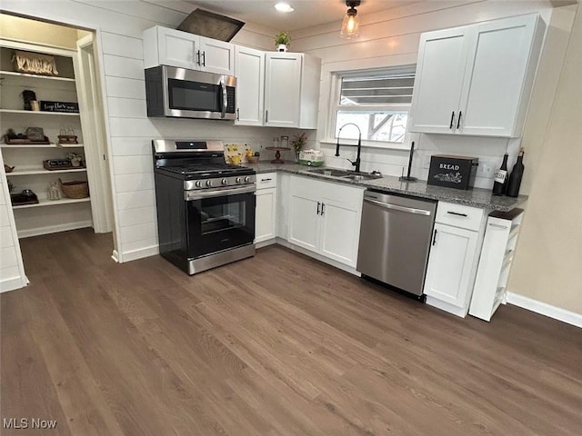 kitchen with stainless steel appliances, white cabinetry, dark wood-type flooring, and sink